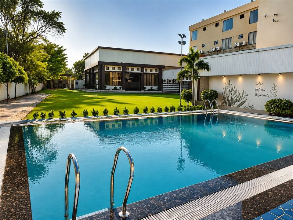 Outdoor swimming pool and garden lawn at Hotel Royal Celebration Inn, Ajmer Road, Jaipur